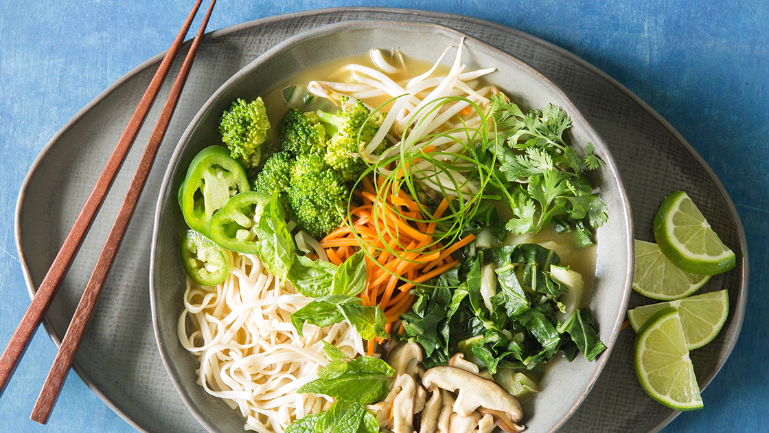 Bowl of vegan pho and limes.