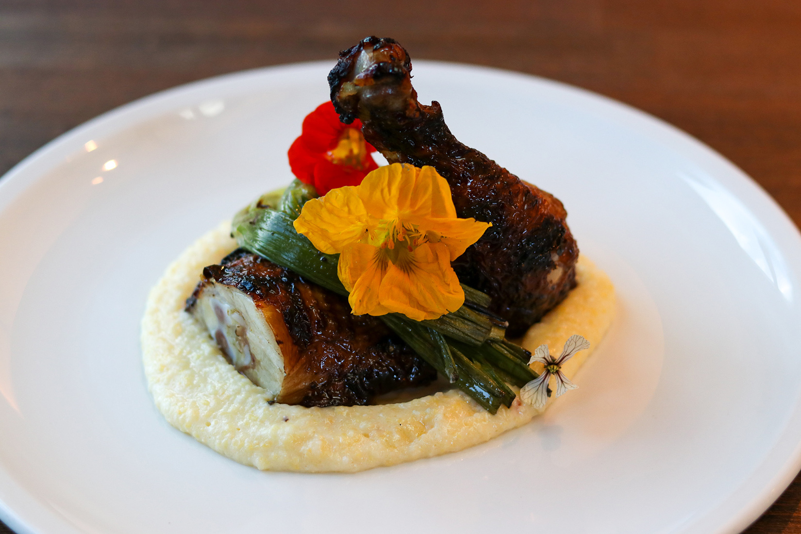 A plate of chicken thighs on polenta.