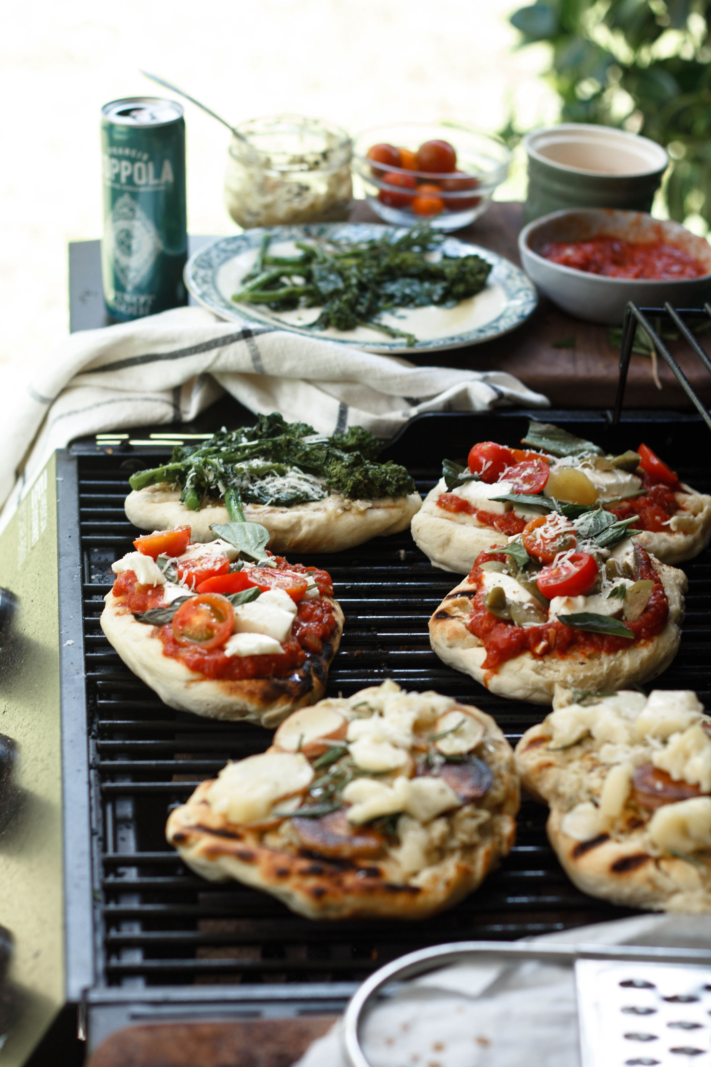 Small pizzas with toppings on a grill.