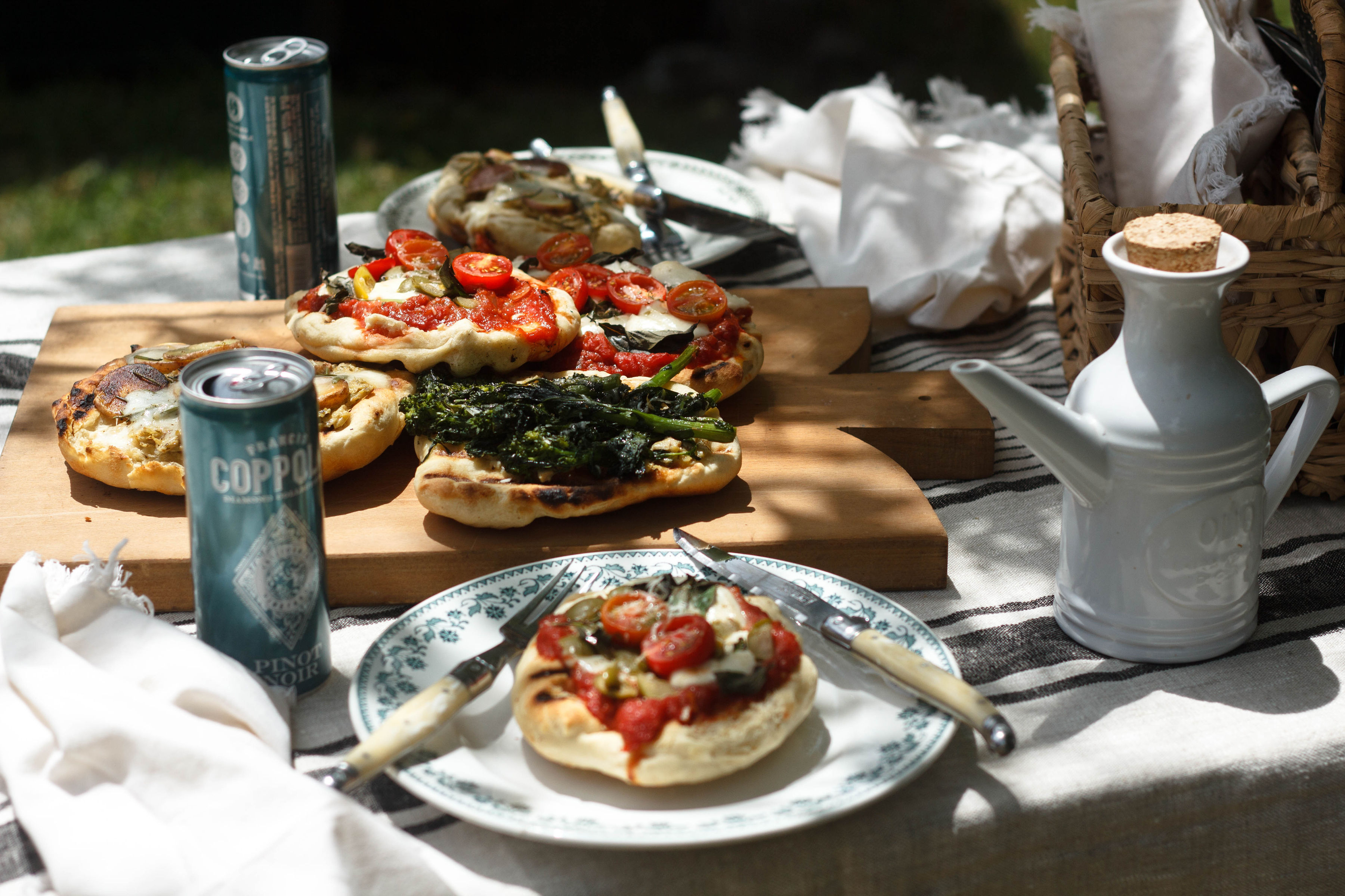 A cutting board with an assortment of grilled pizzas.