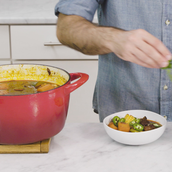 Man cooking over an enameled cast iron pot. 