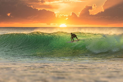 Surfer riding a wave at sunset.
