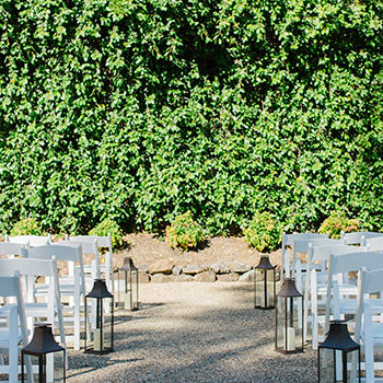 White chairs with lanterns  along the isle set up for a wedding.